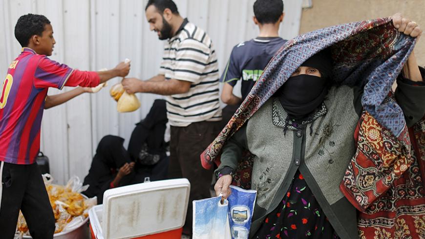 An elderly woman leaves a charity food assistance center after receiving her ration in Yemen's capital Sanaa July 1, 2015. REUTERS/Khaled Abdullah - RTX1INNM