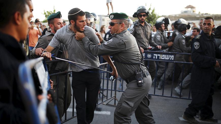 A Jewish settler (2nd L) scuffles with an Israeli border police officer near buildings slated for demolition by order of Israel's high court, in the West Bank Jewish settlement of Beit El, near Ramallah July 28, 2015. Israeli police said on Tuesday that forces were deployed to the settlement in the occupied West Bank in order to prevent people from barricading themselves inside the structures known as the "Drainhoff" buildings. REUTERS/Amir Cohen TPX IMAGES OF THE DAY - RTX1M69K