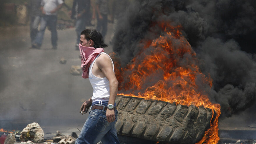 Pro-government loyalists set barricades and burn tyres on the main highway leading to southern Lebanon in Jiyeh area, south of Beirut, May 8, 2008. Pro-government activists blocked a highway linking Beirut to the mainly Shi'ite south with burning tyres and mounds of earth and set up a barricade on the main road to the border with Syria, a strong backer of Hezbollah. REUTERS/Ali Hashisho (LEBANON) - RTX5HB9