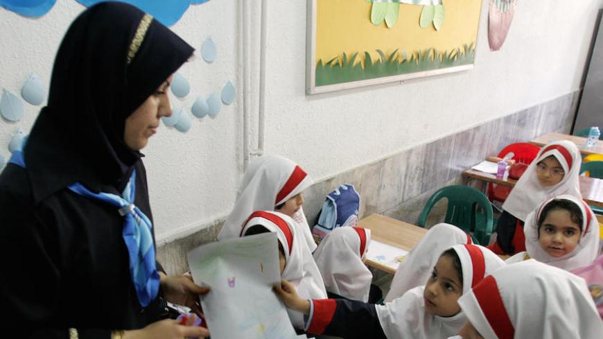 Tehran, IRAN:  An Iranian girl gives her drawing to a teacher in the clasroom at Sizdah Abban school in north of Tehran 01 October 2006. Iranian students went back to school a week ago. US President George W. Bush signed into law yesterday a set of sanctions targeting foreign countries that continue nuclear cooperation with Iran and sell it advanced weaponry. The measure, passed by the Senate Saturday after clearing the House of Representatives a day earlier, came as Iran and the European Union are engaged 