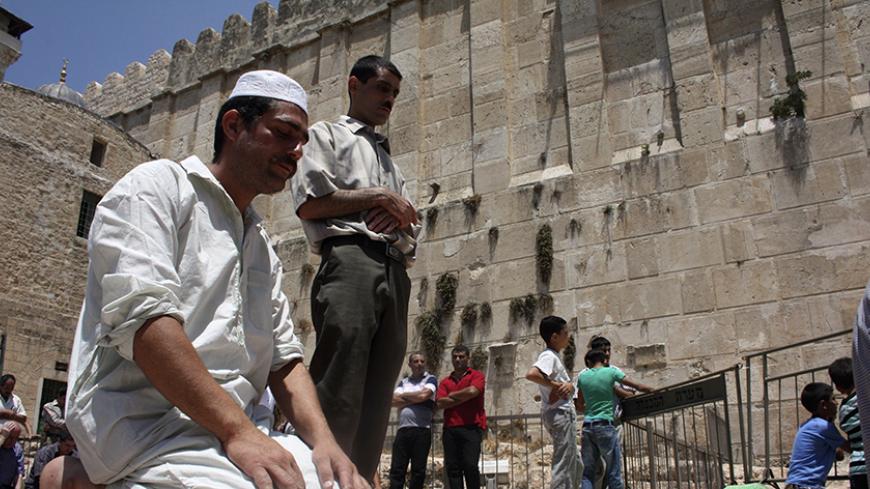 Muslim men pray near the al-Ibrahimi mosque, also known as the Tomb of the Patriarchs, in the West Bank city of Hebron during the first Friday of the holy month of Ramadan August 5, 2011. REUTERS/Mussa Qawasma (WEST BANK - Tags: RELIGION) - RTR2PMYE