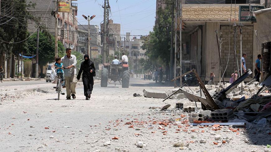 A family walks at a site hit by what activists said was an airstrike by forces loyal to Syria's President Bashar al-Assad, at the eastern Ghouta of Damascus June 5, 2015. REUTERS/Amer Almohibany - RTX1F8QO