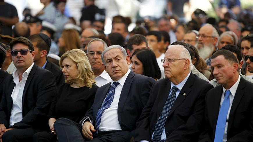Israel's Prime Minister Benjamin Netanyahu (C) and his wife Sara (2nd R) sit next to President Reuven Rivlin (2nd L) during a ceremony on Mount Herzl in Jerusalem commemorating soldiers who died in the 2014 Gaza war July 6, 2015. The ceremony marked the first anniversary of Israel launching "Operation Protective Edge" in response to rockets fired by militants from the Hamas-ruled Gaza Strip. REUTERS/Ronen Zvulun - RTX1J9ZU