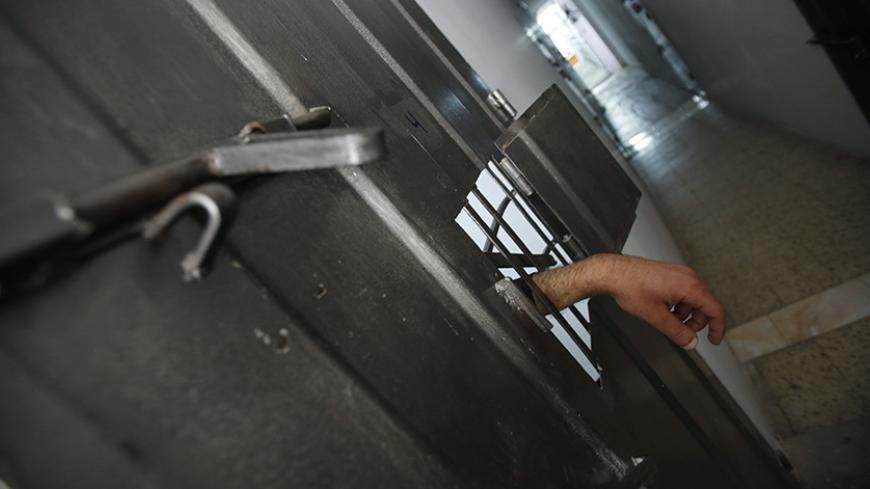 The hand of an alleged Palestinian collaborator hangs out of his cell as he speaks with a security guard inside a Hamas-run prison in Gaza City April 23, 2013. The Islamist Hamas government, which is pledged to Israel's destruction by force of arms, is lauding a recent campaign to root out informants in its midst, which it hopes will deprive Israel of a subtle but effective tool. Picture taken April 23, 2013. To match Feature PALESTINIANS-HAMAS/SPIES   REUTERS/Suhaib Salem (GAZA - Tags: POLITICS) - RTXZEXX