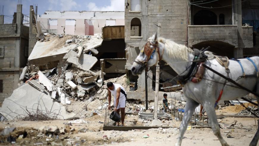 A Palestinian man uses a bucket of water as he reconstructs his house, on June 28, 2015, which was destroyed during the 50-day war between Israel and Hamas militants in the summer of 2014, in the Eastern Gaza City Shujaiya neighbourhood. AFP PHOTO / MOHAMMED ABED (Photo credit should read MOHAMMED ABED/AFP/Getty Images)