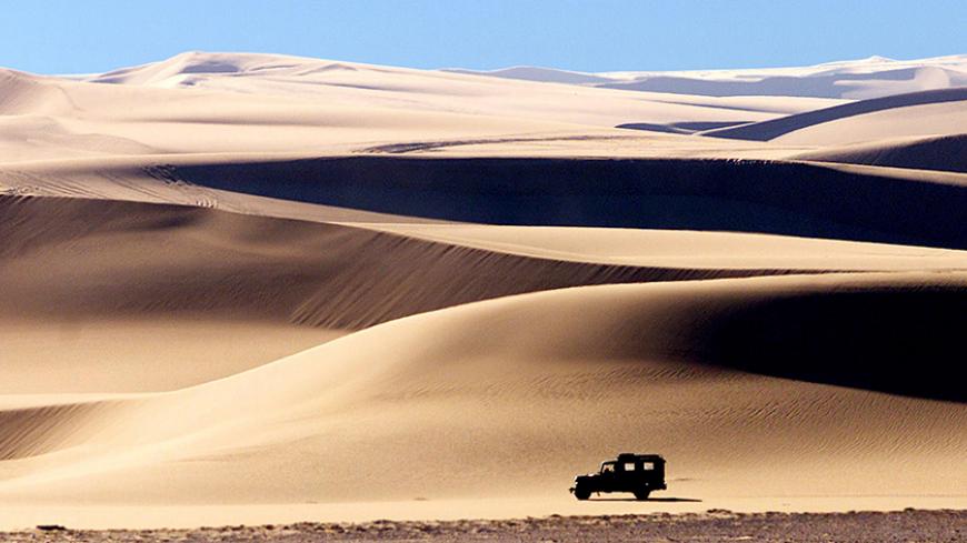A four wheel drive vehicle crosses the sand dunes in the late afternoon sun near the Egyptian western desert oasis of Siwa.  A four wheel drive vehicle crosses the sand dunes in the late afternoon sun near Egypt's western desert oasis of Siwa on February 3, 2002. HIGH RESOLUTION FILE BLIFE REUTERS/Aladin Abdel Naby REUTERS BOOKS ON THE ROAD BOOK - RTR13V9