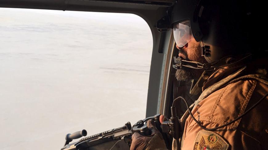 A soldier from the United Arab Emirates armed with a machine gun watches over Yemeni territory on a Chinook helicopter on the frontline conflict zone of Marib in central Yemen September 16, 2015. Armed with high-tech Western weaponry, Gulf Arab soldiers are fighting with newfound determination against what they see as the expanding influence of Iran, their non-Arab and Shi'ite Muslim arch-foe, in a war that has ravaged Yemen for six months. The oil-producing province of Marib has become a key battlefield be