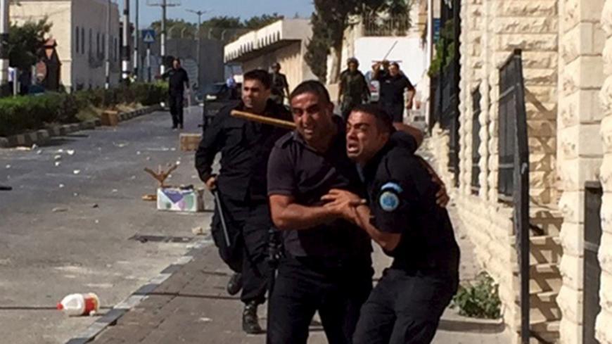 A Palestinian policeman reacts next to fellow police officers as he tries to prevent Palestinian demonstrators (not pictured) from reaching an Israeli checkpoint during a protest against the Israeli police raid on Jerusalem's al-Aqsa mosque on Tuesday, in the occupied West Bank city of Bethlehem September 18, 2015. Israel deployed hundreds of extra police around the Old City of Jerusalem on Friday after Palestinian leaders called for a 'day of rage' to protest at new Israeli security measures. REUTERS/Luke