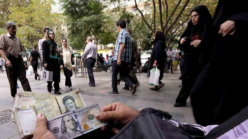 A money changer displays U.S. and Iranian banknotes at the Grand Bazaar in central Tehran October 7, 2015. REUTERS/Raheb Homavandi/TIMA ATTENTION EDITORS - THIS PICTURE WAS PROVIDED BY A THIRD PARTY. REUTERS IS UNABLE TO INDEPENDENTLY VERIFY THE AUTHENTICITY, CONTENT, LOCATION OR DATE OF THIS IMAGE. FOR EDITORIAL USE ONLY. NOT FOR SALE FOR MARKETING OR ADVERTISING CAMPAIGNS. NO THIRD PARTY SALES. NOT FOR USE BY REUTERS THIRD PARTY DISTRIBUTORS. THIS PICTURE IS DISTRIBUTED EXACTLY AS RECEIVED BY REUTERS, AS 