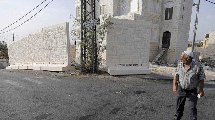A Palestinian man walks past a newly erected temporary concrete wall that measures around 10 meters in length, in the East Jerusalem neighbourhood of Jabel Mukaber October 19, 2015. REUTERS/Ammar Awad - RTS52AL