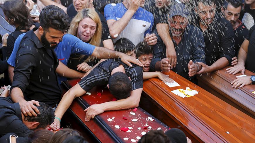 Relatives of the Safwan family, that drowned on a boat carrying them from Turkey to Greece, mourn on their coffins during their funeral in Beirut's southern suburb of Ouzai, Lebanon October 22, 2015. Seven members of a Lebanese family who died trying to reach Greece by boat were buried on Thursday in Beirut and survivors described watching their loved ones perish before their eyes. Members of the Safwan family said the dead, who included a pregnant woman and two children, had left poor living conditions in 