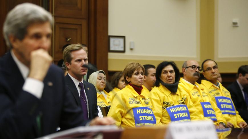 The U.S. families of Iranian dissidents, members of Iran's opposition movement Mujahedin-e Khalq (MEK) who reside in Camp Liberty in Iraq, look on as U.S. Secretary of State John Kerry testifies on agreements over Iran's nuclear programs, before the House Foreign Affairs Committee on Capitol Hill in Washington, December 10, 2013. REUTERS/Jonathan Ernst (UNITED STATES - Tags: POLITICS MILITARY) - RTX16CNF