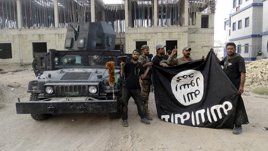 Iraqi security forces hold an Islamist State flag which they pulled down at the University of Anbar, in Anbar province July 26, 2015. Iraqi security forces entered the University of Anbar in the western city of Ramadi on Sunday and clashed with Islamic State militants inside the compound, the joint operations command said in a statement. REUTERS/Stringer - RTX1LW6L