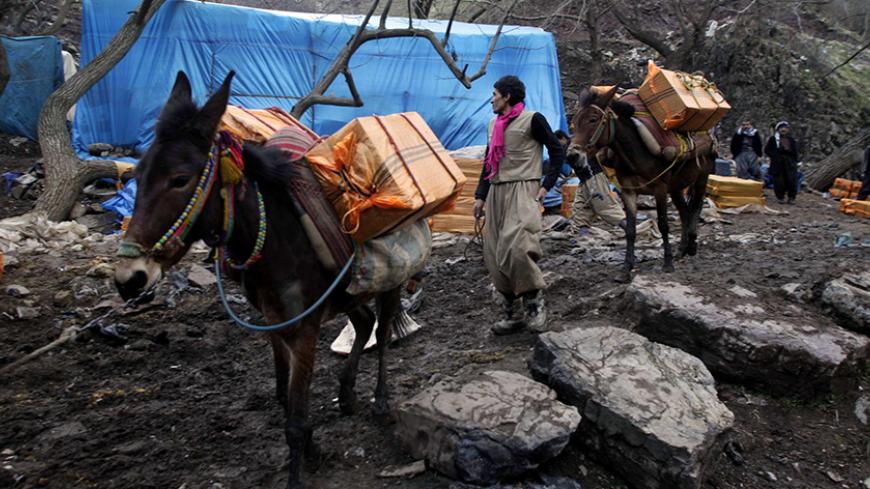 A member of a smuggling group holds the leash of a horse carrying alcoholic drinks during a smuggling operation to Iran at the border near Sulaimaniya, 260 km (160 miles) northeast of Baghdad January 26, 2012. Border security forces repeatedly clash with smugglers who use the dark and rugged area to facilitate their operations. Picture taken on January 26, 2012.  REUTERS/Stringer (IRAQ - Tags: CRIME LAW ANIMALS TPX IMAGES OF THE DAY) - RTR2WXC1