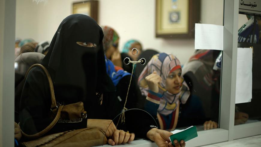 Palestinian Hamas-hired civil servants wait to receive payment at a post office in Gaza City October 29, 2014. Some 24,000 civil servants hired by the Islamist group Hamas, many of whom have not received a full salary in almost a year, finally got some pay on Wednesday from the new Palestinian unity government based in the West Bank. The funds were supplied by the gas-rich kingdom of Qatar, which is an ally of Hamas. But the fact the cash was delivered by the West Bank administration gave a boost to hopes t