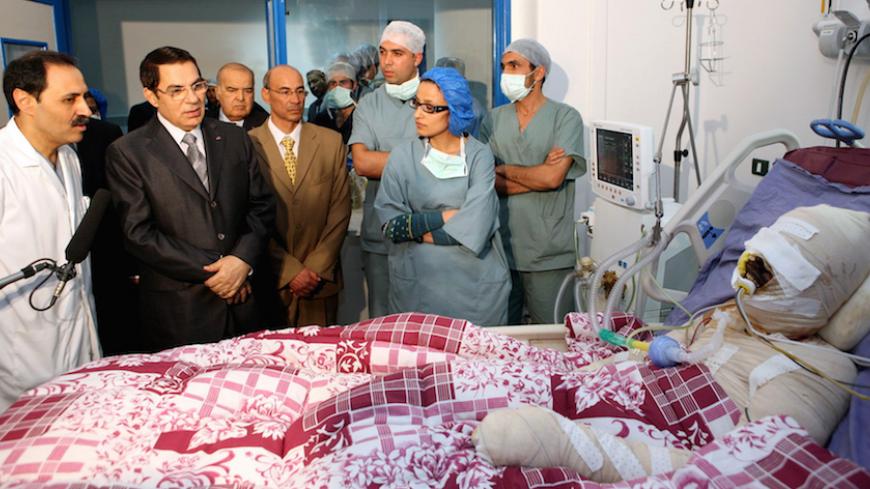 A handout picture released by the Tunisian Presidency shows Tunisian president Zine El-Abidine Ben Ali (2nd L) looking at Mohamed Al Bouazzizi (R), during his visit at the hopital in Ben Arous near Tunis on December 28, 2010. Mohamed Al Bouazzizi, a 26-year-old university graduate, who was forced to sell fruit and vegetables on the streets, doused himself in petrol and set himself alight on December 17, which left him in a serious condition with severe burns. Days of rioting in Tunisia by mostly jobless