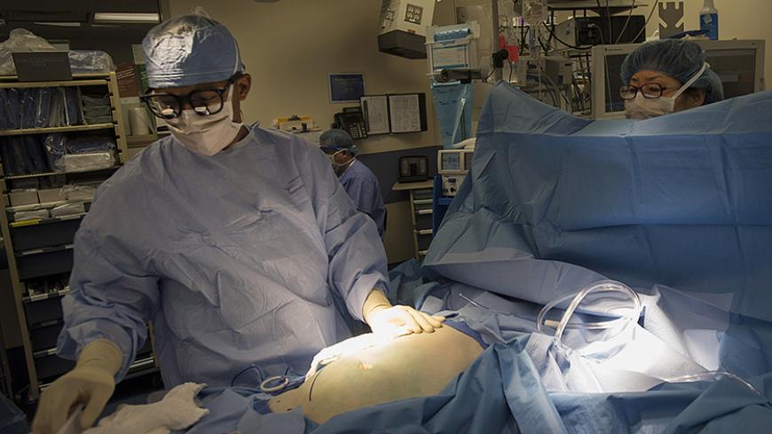 A surgical team prepares Adam Abernathy for surgery to receive a donated kidney as part of a five-way organ transplant swap in New York, August 1, 2012. Abernathy's partner David Ferguson donated a kidney for transplant to a stranger while at the same time someone donated a kidney to Abernathy as part of chain of kidney donations that allowed five people to receive a transplanted kidney of a two day period. The health dangers for kidney donors is believed to be low. The risk of death from the surgery is 1 i