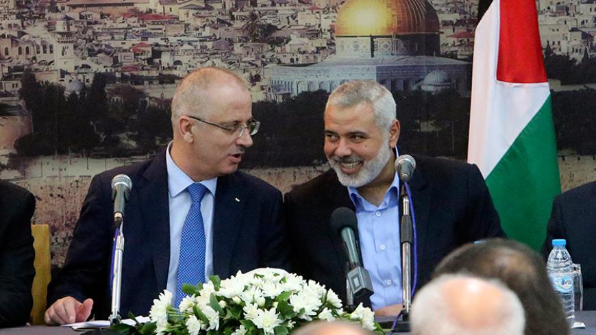Senior Hamas leader Ismail Haniyeh (R) speaks with Palestinian Prime Minister Rami Hamdallah at Haniyeh's house in Gaza City October 9, 2014. Hamdallah arrived in the Hamas-dominated Gaza Strip on Thursday and convened the first meeting of a unity government there since a brief civil war in 2007 between Hamas and forces loyal to the Fatah party. REUTERS/Ibraheem Abu Mustafa (GAZA - Tags: POLITICS CIVIL UNREST) - RTR49J4R