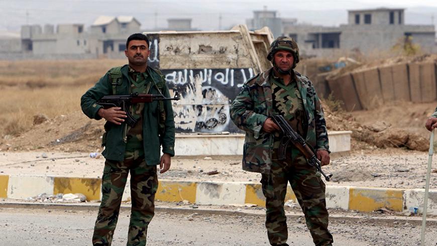 Kurdish peshmerga forces stand in the street after Yazidi people loot houses in the town of Sinjar, Iraq November 16, 2015. Before it was overrun by Islamic State, Sinjar and the surrounding villages were home to about 200,000 people, mainly Kurdish and Arab Muslims - both Sunni and Shi'ite - as well as Christians and Yazidis, a faith that combines elements of several ancient Middle Eastern religions. Now the town is largely deserted. But in a row of houses used by Islamic State fighters, there were signs o