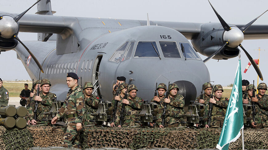 Lebanese army soldiers stand with displayed weapons that they received during a ceremony at Beirut airport airbase April 20, 2015. The first shipment of French weapons and military equipment arrived in Lebanon on Monday under a Saudi-funded deal worth $3 billion to bolster the Lebanese army's fight against militants encroaching from neighboring Syria. The Saudi Arabia's national flag is displayed during the ceremony. REUTERS/Mohamed Azakir  - RTX19H7S