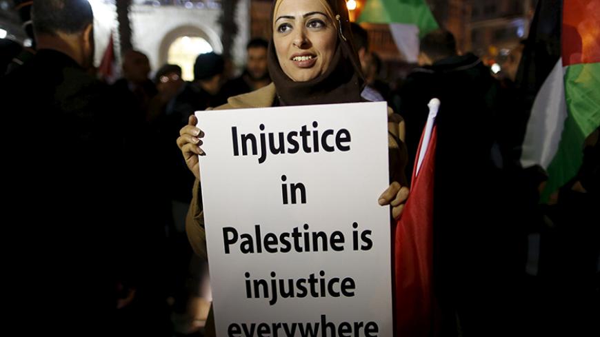 A Palestinian woman holds a sign during a protest against the visit of U.S. Secretary of State John Kerry to the West Bank city of Ramallah, in Ramallah November 24, 2015. REUTERS/Ammar Awad   - RTX1VN8K