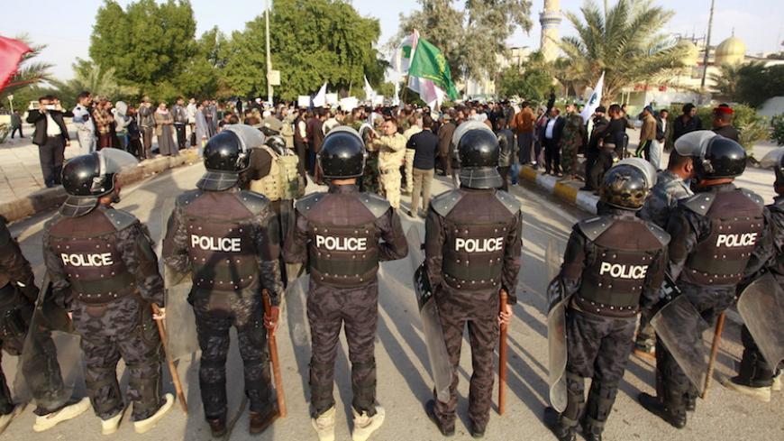 Riot police stand in front of protesters during a demonstration against Turkish military deployment in Iraq, in Najaf, Iraq, December 12, 2015. REUTERS/Alaa Al-Marjani - RTX1YDSC