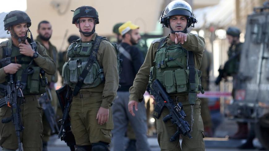 An Israeli soldier gestures as he stands guard with others at the scene of what an Israeli police spokeswoman said was a car-ramming attempt by a Palestinian at the West Bank checkpoint of Qalandia, near Ramallah, December 18, 2015. REUTERS/Mohamad Torokman - RTX1ZANG