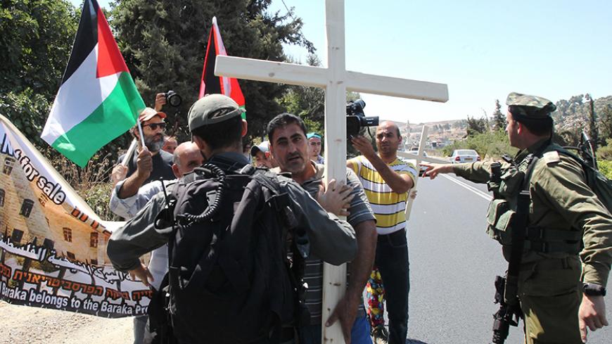 Palestinian, Israeli and Christian foreign activists confront Israeli soldiers as they walk towards Beit al-Baraka, a church compound, situated between the Al-Arub refugee camp and the city of Hebron in the occupied West Bank during a demonstration condemning the Israeli occupation, on August 15, 2015. AFP PHOTO / HAZEM BADER (Photo credit should read HAZEM BADER/AFP/Getty Images)