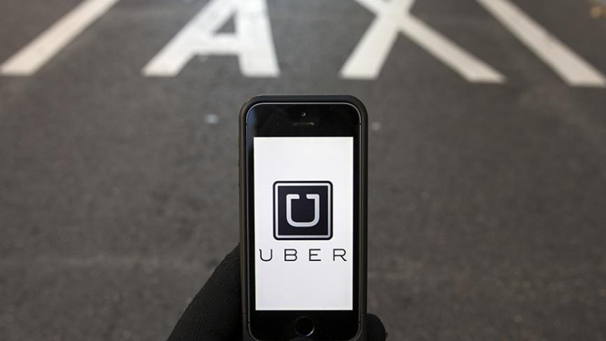 The logo of car-sharing service app Uber on a smartphone over a reserved lane for taxis in a street is seen in this photo illustration taken in Madrid on December 10, 2014. A Madrid judge has ordered U.S.-based online car booking company Uber to cease operations in Spain, the latest ban on the popular service. Taxi drivers around the world consider Uber unfairly bypasses local licensing and safety regulations by using the internet to put drivers in touch with passengers. REUTERS/Sergio Perez (SPAIN - Tags