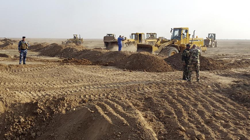 People operate heavy machinery during the building of a new road between Diyala province and Samarra December 21, 2014. A Shi'ite paramilitary organization is constructing a road to strengthen its positions across the mixed areas of Diyala and neighbouring Salahuddin province. The Badr Organization, a leading political party and militia with ties to Iran, is supervising the new road, which leads to Samarra. It means Badr can resupply troops guarding Samarra, currently surrounded by Islamic State, and the 3