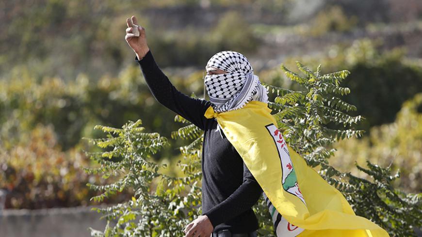 A Palestinian protester holds a stone during clashes with Israeli troops in the West Bank town of Halhul, north Hebron November 14, 2015. REUTERS/Mussa Qawasma    - RTS70G7