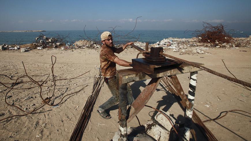 A Palestinian worker straightens scrap metal collected from the rubble of a hotel in Gaza City that was destroyed during Israel's three-week offensive nearly two years ago November 7, 2010. Thousands of Gazans, mainly young men and boys, go close to a no-go border zone in the Gaza Strip daily to pick over the wreckage of factories and houses flattened by Israel in the past few years in its conflict with Islamist Hamas militants who control the enclave. REUTERS/Suhaib Salem (GAZA - Tags: POLITICS SOCIETY) -