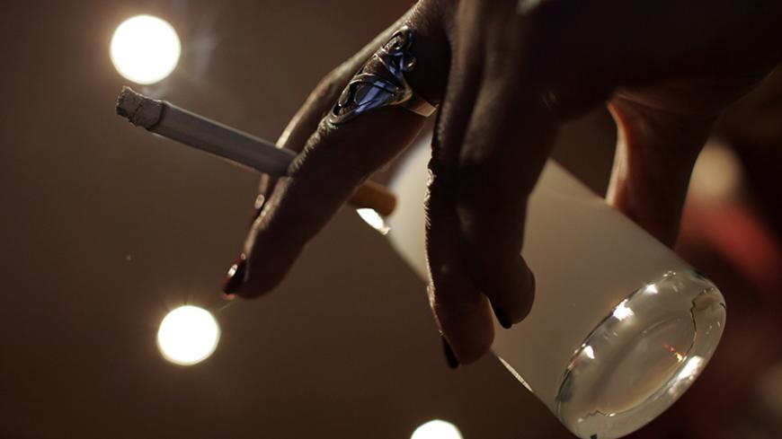 A woman smokes in a bar as she drinks the Turkish traditional beverage Raki in Ankara February 12, 2008. Turkey is the eighth biggest cigarette market in the world, with nearly 60 percent of male adults estimated to smoke. Six global cigarette producers and state-run Tekel compete for the lucrative market. Picture taken February 12, 2008. To match feature TURKEY-CIGARETTES/     REUTERS/Umit Bektas (TURKEY) - RTR1X0MR