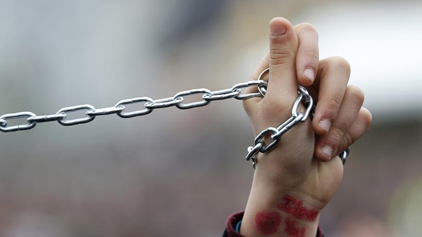 A Turkish Shi'ite girl holds a chain as she mourns during an Ashura procession in Istanbul November 24, 2012. Muslims all over the world mourn the slaying of Imam Hussein during the first ten days of the Islamic month of Muharram. Imam Hussein was killed by his political rivals along with 72 companions in the seventh century battle of Kerbala. REUTERS/Murad Sezer (TURKEY - Tags: ANNIVERSARY RELIGION) - RTR3ATV2