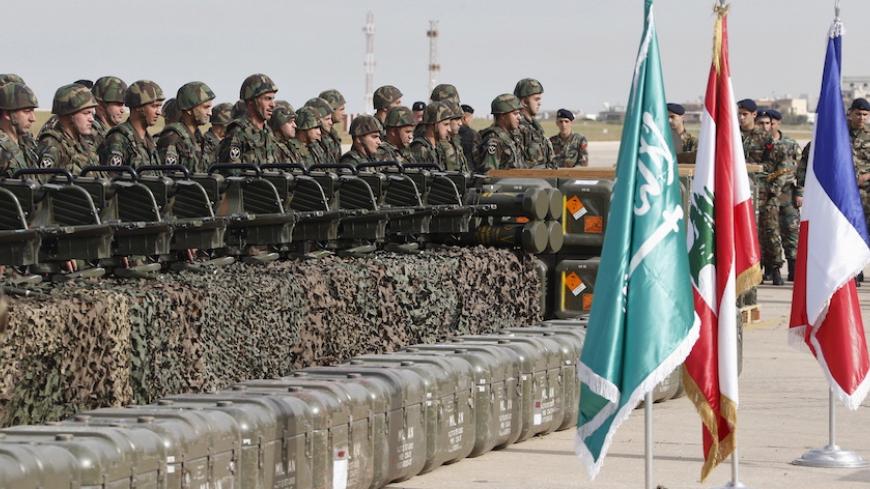 Lebanese army soldiers stand next to displayed weapons that they received during a ceremony at Beirut airport airbase April 20, 2015. The first shipment of French weapons and military equipment arrived in Lebanon on Monday under a Saudi-funded deal worth $3 billion to bolster the Lebanese army's fight against militants encroaching from neighboring Syria. (From L to R) The national flags of Saudi Arabia, Lebanon and France are displayed during the ceremony. REUTERS/Mohamed Azakir  - RTX19H2B