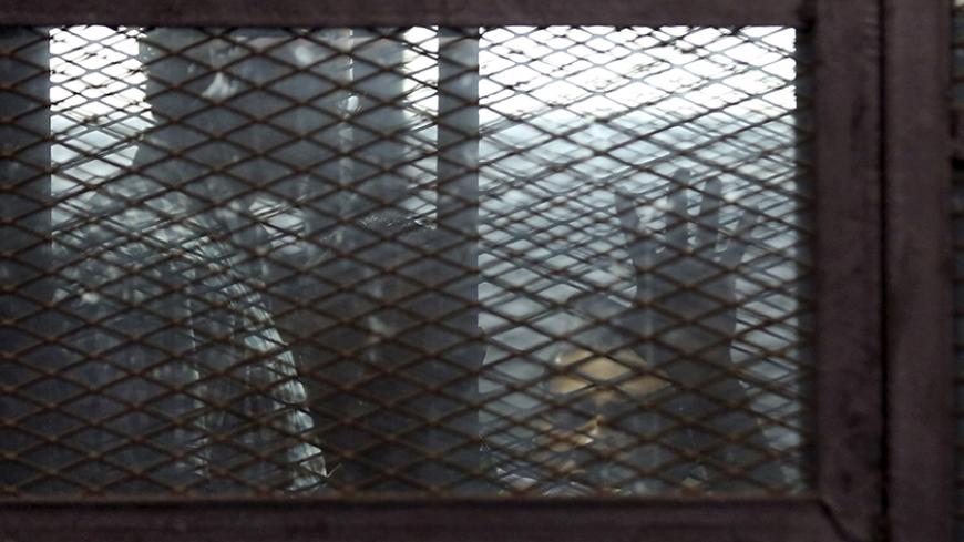 Al Jazeera television journalists Mohamed Fahmy and Baher Mohamed are seen behind bars before hearing the verdict at a court in Cairo, Egypt, August 29, 2015. An Egyptian court sentenced three Al Jazeera TV journalists to three years in prison on Saturday for operating without a press licence and broadcasting material harmful to Egypt, a case that has triggered an international outcry. The verdict in a retrial was issued against Mohamed Fahmy, a naturalised Canadian who has given up his Egyptian citizenshi