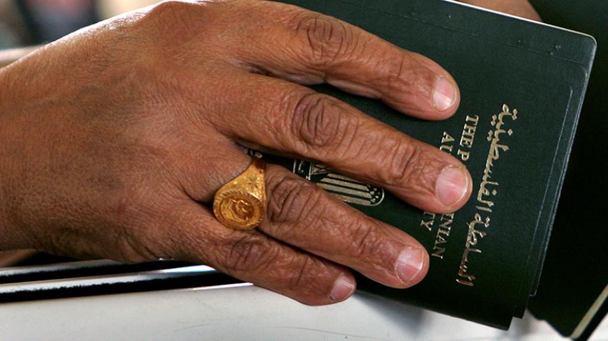 A Palestinian woman holds her passport as she waits to cross the Rafah border crossing in Gaza Strip November 27, 2005. Palestinians asserted control for the first time over an international frontier on Saturday as hundreds of Gazans moved across a newly opened terminal at Rafah into neighbouring Egypt. REUTERS/Suhaib Salem - RTR1BP61