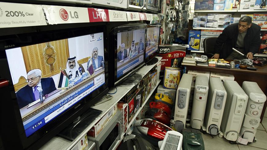 A Palestinian man watches a television broadcast showing Palestinian President Mahmoud Abbas and Hamas leader Khaled Meshaal in Doha, in his appliance store in Gaza City February 6, 2012. Rival Palestinian factions Fatah and Hamas agreed at a meeting in Qatar on Monday to form a unified Palestinian government for the West Bank and Gaza headed by Fatah chief Abbas, a senior Palestinian official said. REUTERS/Ibraheem Abu Mustafa (GAZA - Tags: POLITICS) - RTR2XEA6