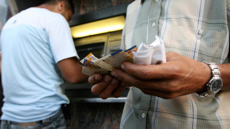 Palestinian government employees withdraw money from automated teller machines (ATMs) of the Bank of Palestine in Gaza City June 4, 2006. REUTERS/Ahmed Jadallah (PALESTINIAN TERRITORIES) - RTR1E36U