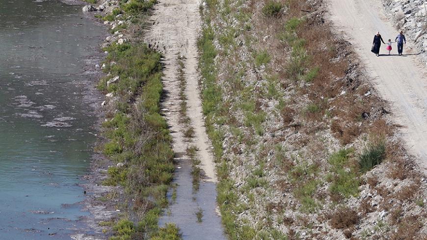 A family takes a stroll next to a reservoir in Myrtoy that will receive fresh water from Turkey via a water pipeline project linking Turkey to northern Cyprus Oct 17 2015. The 106-kilometre (66-mile) pipeline will transport some 75 million cubic metres (2.6 billion cubic feet) of water annually to northern Cyprus, a breakaway Turkish Cypriot state recognized only by Ankara. Cyprus suffers from frequent droughts. REUTERS/Yiannis Kourtoglou - RTS4V5V