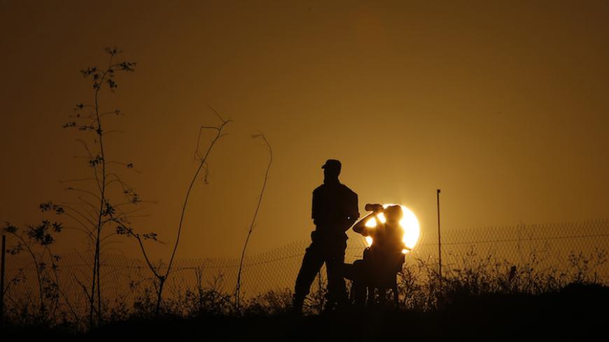 A Palestinian Islamic Jihad militant drinks water as another stands guards during a military drill at sunset in the southern Gaza Strip December 11, 2014. REUTERS/Suhaib Salem (GAZA - Tags: POLITICS CIVIL UNREST MILITARY) - RTR4HNV1