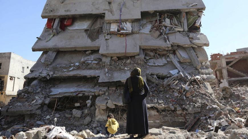 A woman looks at a building, which was damaged during the security operations and clashes between Turkish security forces and Kurdish militants, in the southeastern town of Cizre in Sirnak province, Turkey March 2, 2016. REUTERS/Sertac Kayar - RTS9000