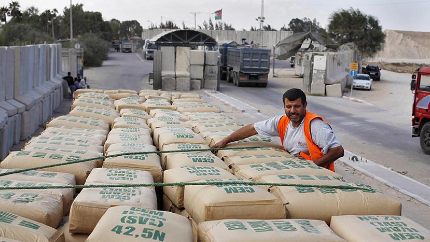 A Palestinian worker checks a truck loaded with cement bags after entering the Gaza Strip through the Kerem Shalom crossing September 22, 2013. Israel began allowing construction material for private projects into the Gaza Strip on Sunday for the first time in six years, in response to a request from Palestinian President Mahmoud Abbas, an Israeli defence official said. REUTERS/Ibraheem Abu Mustafa (GAZA - Tags: POLITICS BUSINESS CONSTRUCTION REAL ESTATE) - RTX13UHI