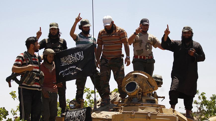 Islamist Syrian rebel group Jabhat al-Nusra members gesture while posing on a tank on Al-Khazan frontline of Khan Sheikhoun, northern Idlib province May 17, 2014. REUTERS/Hamid Khatib (SYRIA - Tags: CIVIL UNREST MILITARY POLITICS CONFLICT) - RTR3PM9N