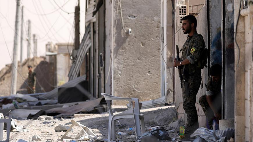 Syrian Democratic Forces (SDF) fighters stand along a damaged street in the Raqqa's al-Sanaa industrial neighbourhood, Syria June 14, 2017. Picture taken June 14, 2017. REUTERS/Rodi Said - RTS175OT