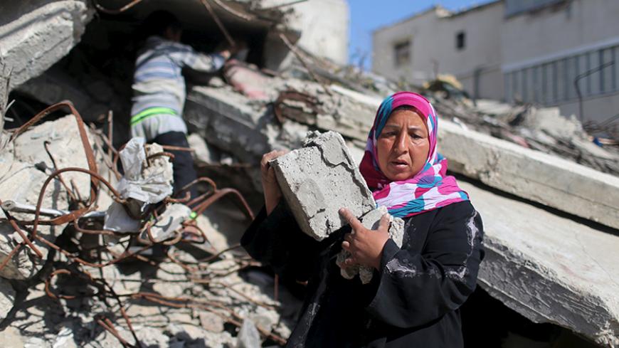 Palestinian woman Jihan Abu Muhsen collects bricks for sale with her son Mohammad from the ruins of a house destroyed during the 2014 war in Khan Younis in the southern Gaza Strip March 8, 2016. Abu Muhsen gathers bricks from the sites of demolished buildings and sells them to recycling factories. She earns around 20 shekels ($5) a day and her 10-year-old son Mohammad helps her when he is not at school. REUTERS/Ibraheem Abu Mustafa SEARCH "GAZA BRICK" FOR THIS STORY. SEARCH "THE WIDER IMAGE" FOR ALL STOR