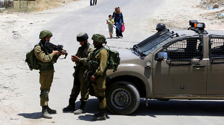 Israeli soldiers stand guard at the entrance of Yatta near the West Bank city of Hebron June 9, 2016. REUTERS/Mussa Qawasma       TPX IMAGES OF THE DAY      - RTSGPGK