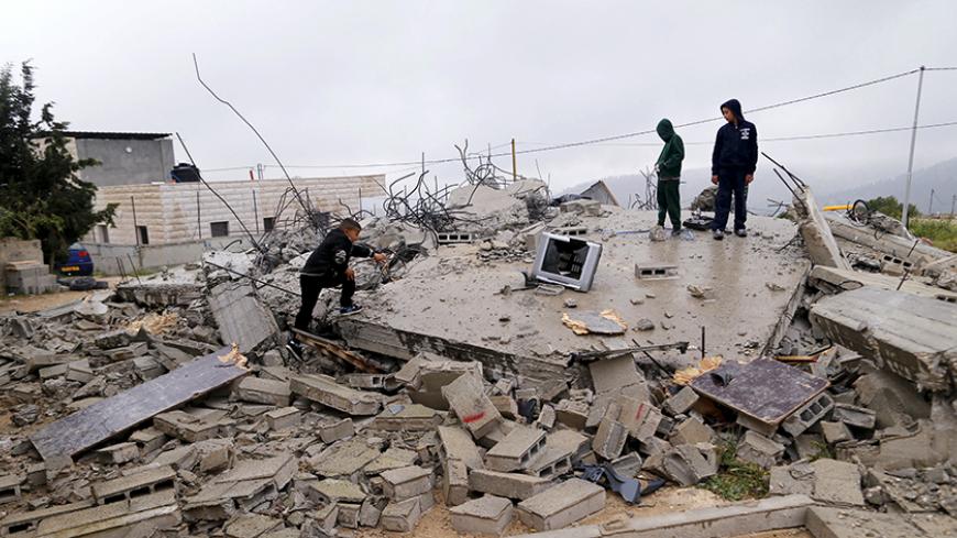 Palestinian boys stand atop the rubble of a house after it was demolished by Israeli bulldozers in the West Bank village of El Walaja near Bethlehem, April 12, 2016. REUTERS/Ammar Awad  - RTX29KX8