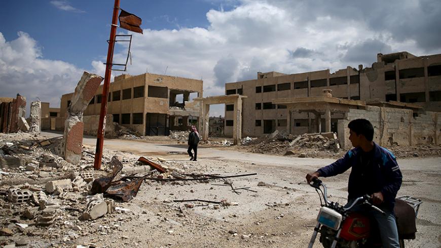 A man rides on a motorbike as another one walks past damaged buildings in the rebel-controlled area of al-Nashabyia town in Eastern Ghouta, Syria April 13, 2016. Picture taken April 13, 2016. REUTERS/Bassam Khabieh  - RTX29YRZ