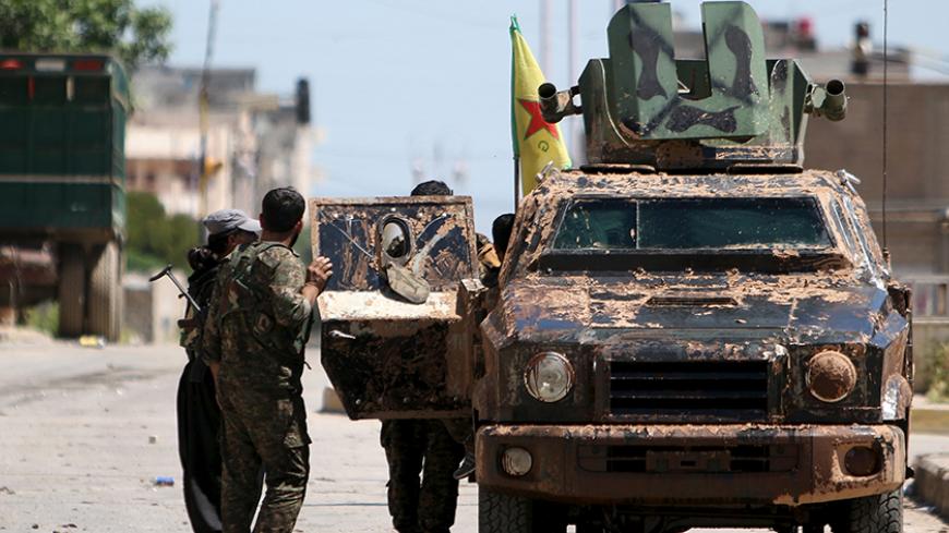 Kurdish fighters from the People's Protection Units (YPG) stand near a military vehilce in the southeast of Qamishli city, Syria, April 22, 2016. REUTERS/Rodi Said - RTX2B6V0